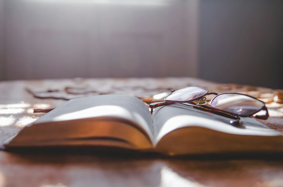 Open book with reading glasses on a desk